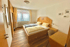 Helles Schlafzimmer mit Holzboden, Doppelbett, Nachttischen, Schrank und Schreibtisch.