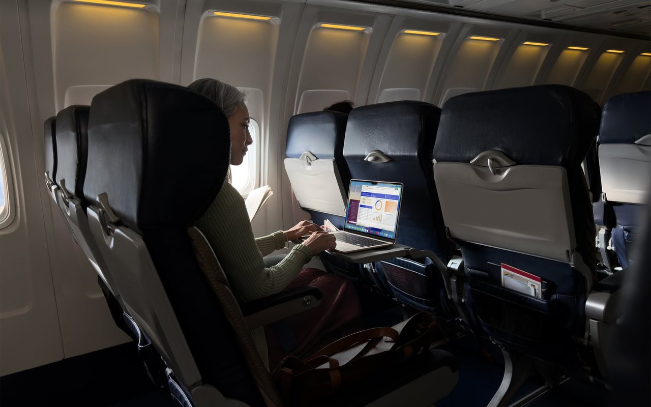 Person arbeitet im Flugzeug am Fensterplatz an einem MacBook Air