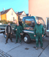 Drei Gärtner in grüner Arbeitskleidung stehen lächelnd vor einem grünen LKW der Firma Gartengestaltung Matthias Müller.