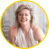 Jenny Kühne mit blonden Haaren, goldenen Ohrringen und einem glänzenden weißen Neckholder-Oberteil.