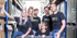 Fünf Personen in schwarzen T-Shirts mit dem RoSS-Logo lächeln in einem Lagerhaus.