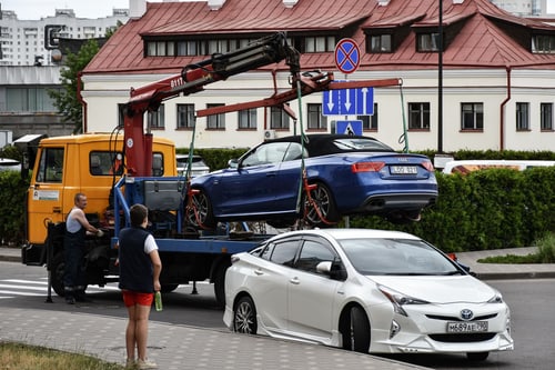 Tow truck loading a car on a city street, illustrating tow truck cost in Cranston, RI