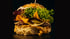 Ein großer Gourmet-Burger mit zwei Patties, Käse, Salat, Nachos und Gurken auf dunklem Hintergrund.