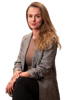 Junge Frau mit langen, hellbraunen Haaren, bekleidet mit einem grauen Blazer über einem braunen Oberteil und schwarzer Hose.