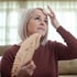 Woman holds a fan to her face and touches her forehead, experiencing fatigue.