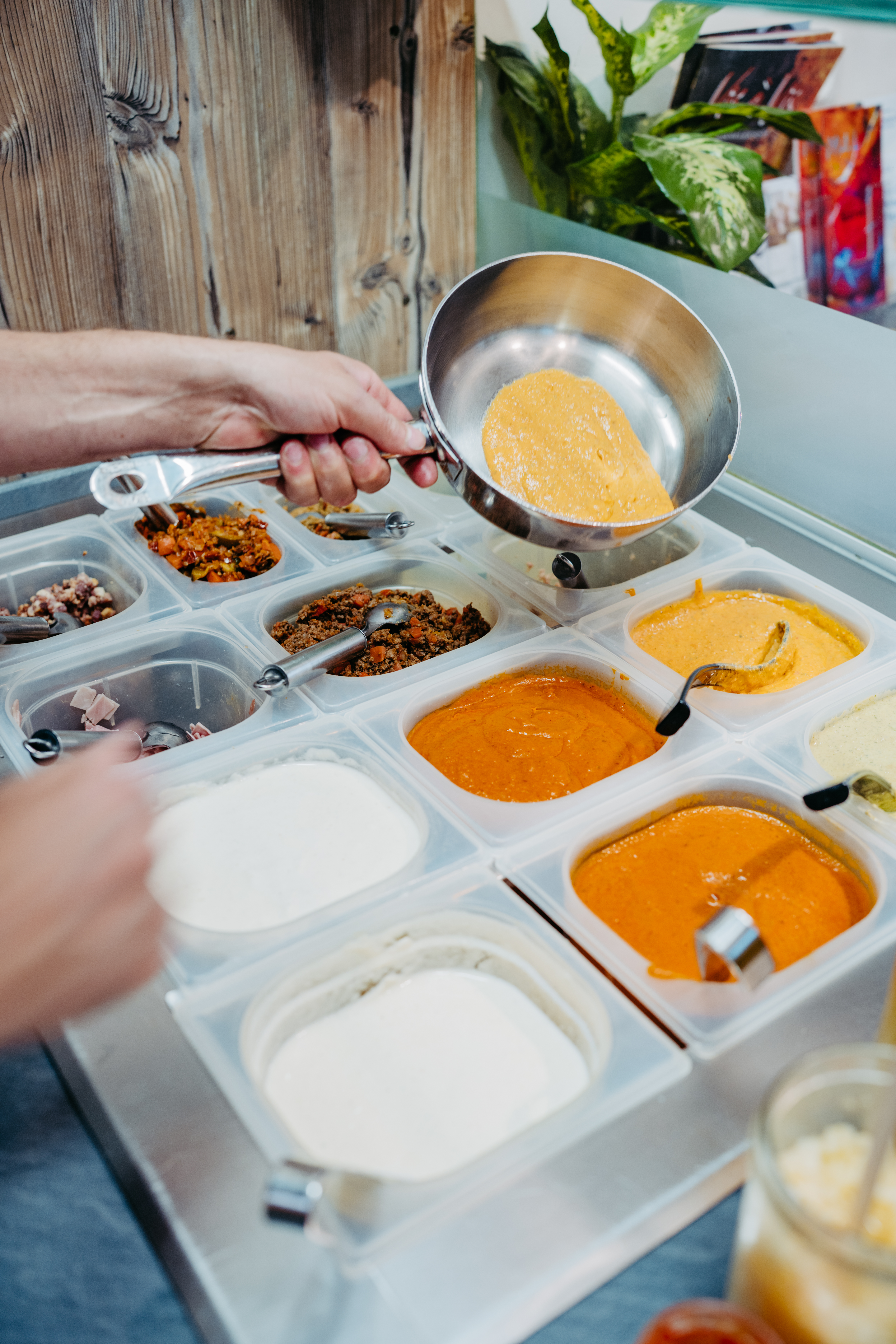 Zutatenstation mit frischen Saucen und Toppings hinter der Theke