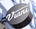 Round black sign with "Viani" in white script lettering, mounted on a timber-framed building.