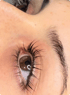 Nahaufnahme eines Auges mit betonten, dunklen Wimpern und einer geformten Augenbraue nach einem Wimpernlifting.