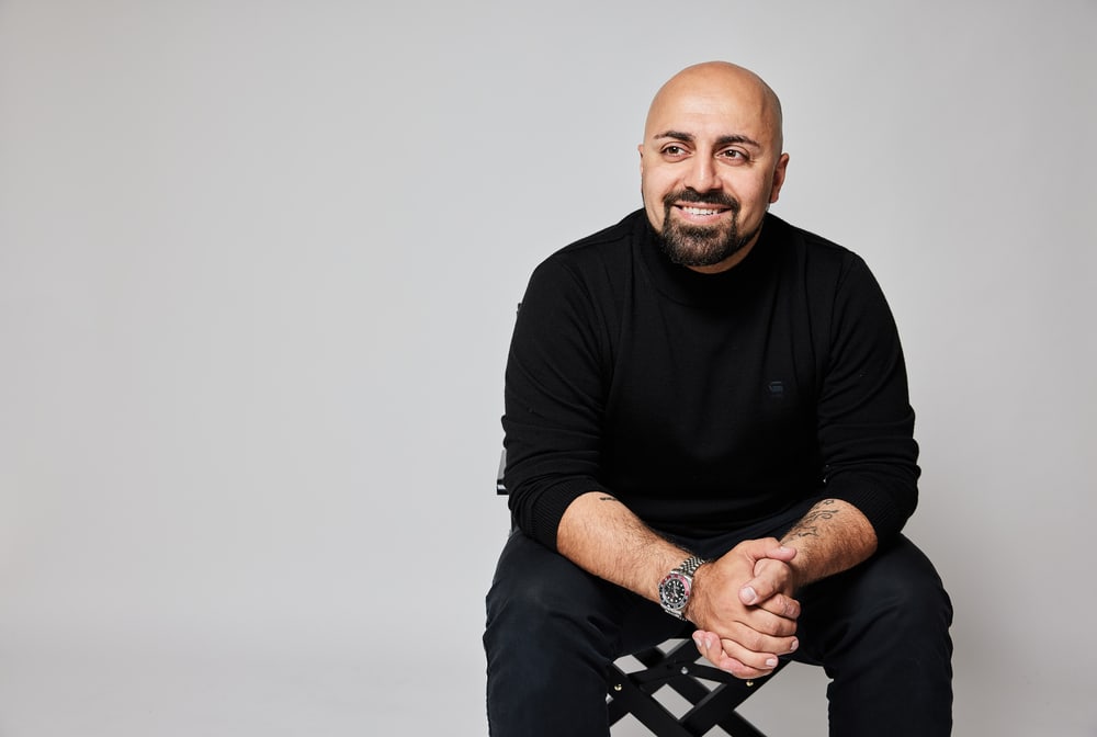 Ali Mahlodji, sitzend im schwarzen Pullover