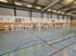 Gruppe von Karatekas in weißen Gis, aufgereiht in einer Sporthalle.