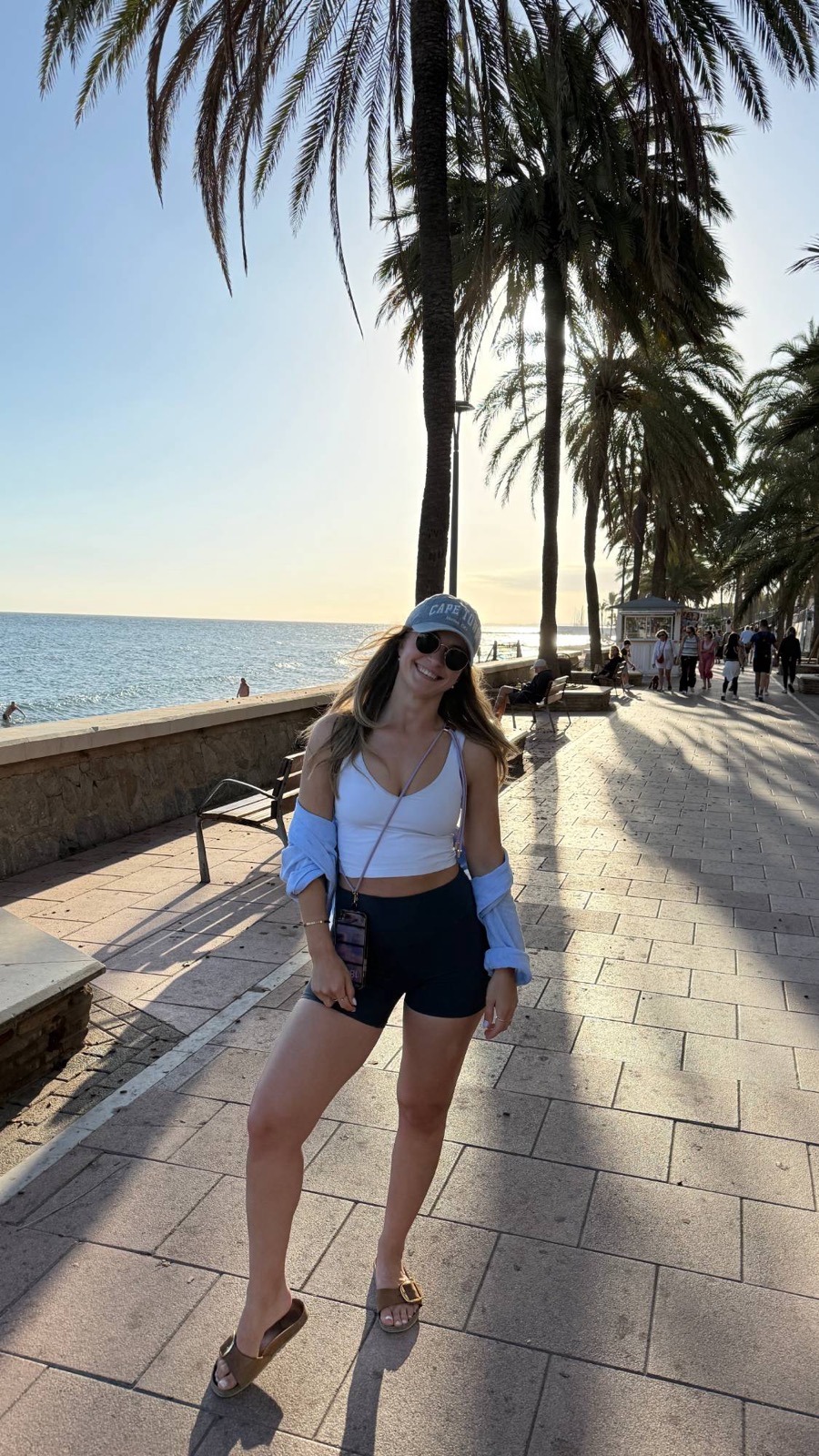 Tatjana Schäfer lächelt auf einer Strandpromenade unter Palmen in die Kamera