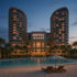 Luxury hotel with two towers, "HOTEL" sign, five stars, a swimming pool, and sandy beach at dusk.