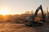 Ein gelber Volvo Kettenbagger arbeitet bei Sonnenuntergang auf einer Baustelle inmitten von Trümmern und Schutt.