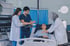 Two doctors and a nurse attend to a male patient lying in a hospital bed.