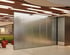 Moderne Schiebewand aus Metalllamellen in einem Bürogebäude mit Holzdecke und integrierter Beleuchtung.