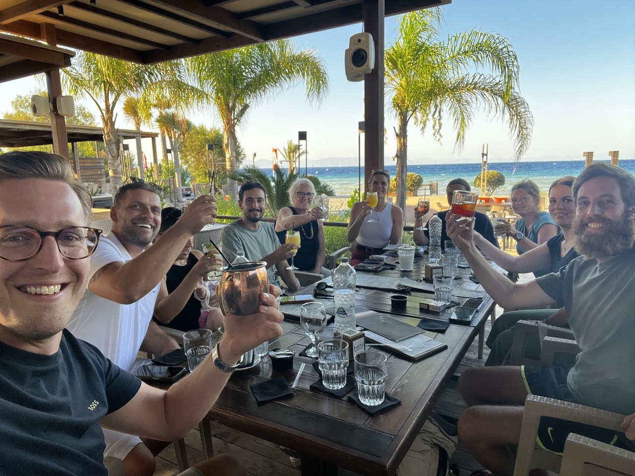 Das Be-Works-Team stoßt in einer Beach-Bar auf Rhodos an