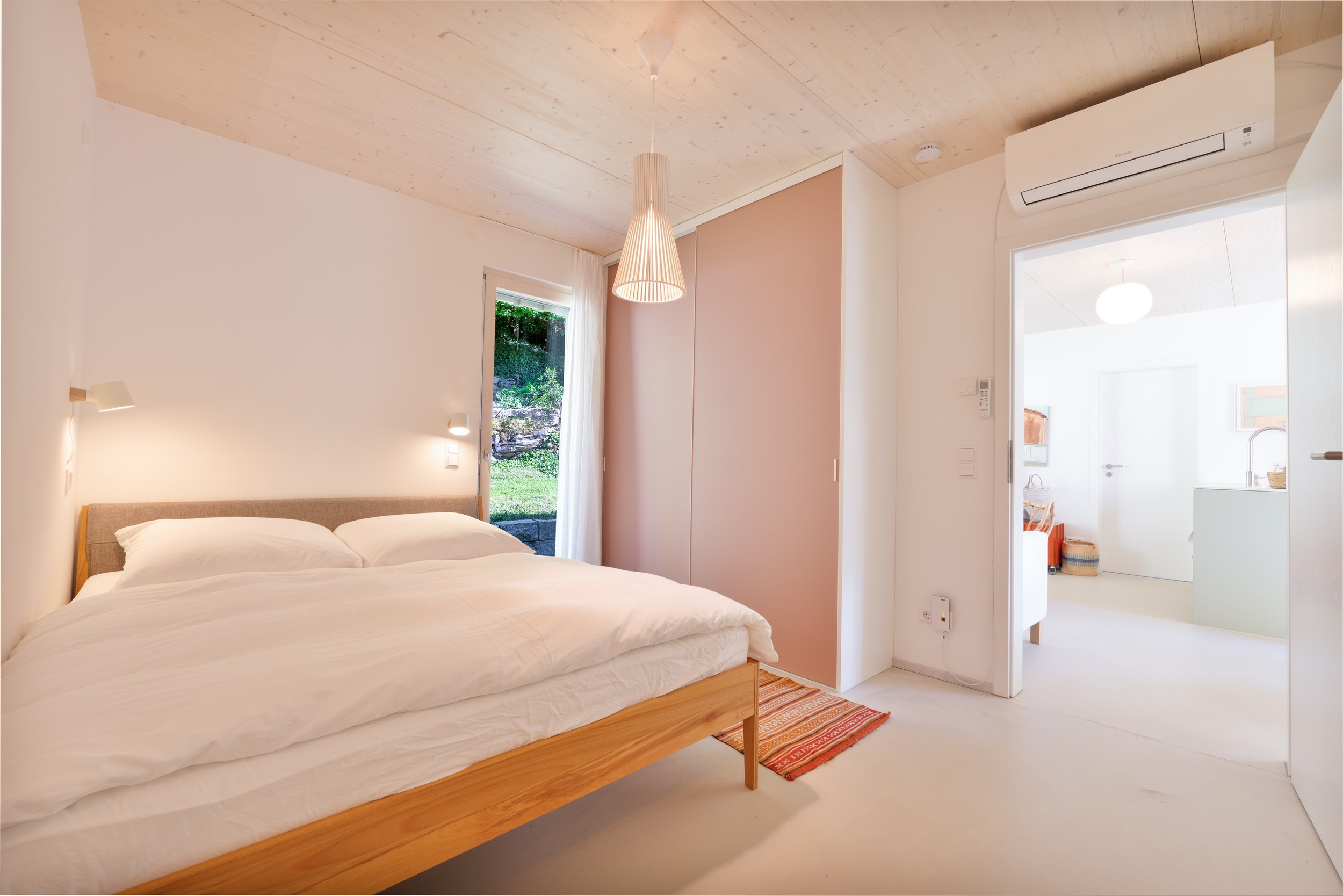 Schlafzimmer mit Holzbett und altrosa Einbauschrank