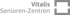 Graues Logo der Vitalis Senioren-Zentren mit dem Schriftzug Vitalis Senioren-Zentren neben einem quadratischen Rahmensymbol.