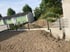 Baustelle im Garten mit Erdhügeln hinter einem anthrazitfarbenen Doppelstabmattenzaun und Beton-L-Steinen.