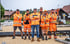 Sechs Bauarbeiter in orangefarbener Schutzkleidung stehen auf Gleisen einer Baustelle und schauen in die Kamera.