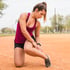 Young female runner checking her calf for any injuries.