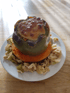 Gefüllte grüne Paprika mit Käse überbacken auf einem Kürbisring und Krautsalat auf weißem Teller.