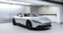 Weißer Ferrari GTC4Lusso mit schwarzem Dach, der in einem modernen Parkhaus steht.