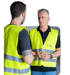 Zwei Handwerker in Warnweste im Gespräch auf der Baustelle