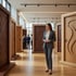 Frau im grauen Hosenanzug steht in einer modernen Ausstellung für hochwertige Innentüren aus Holz mit dekorativen Fräsungen.