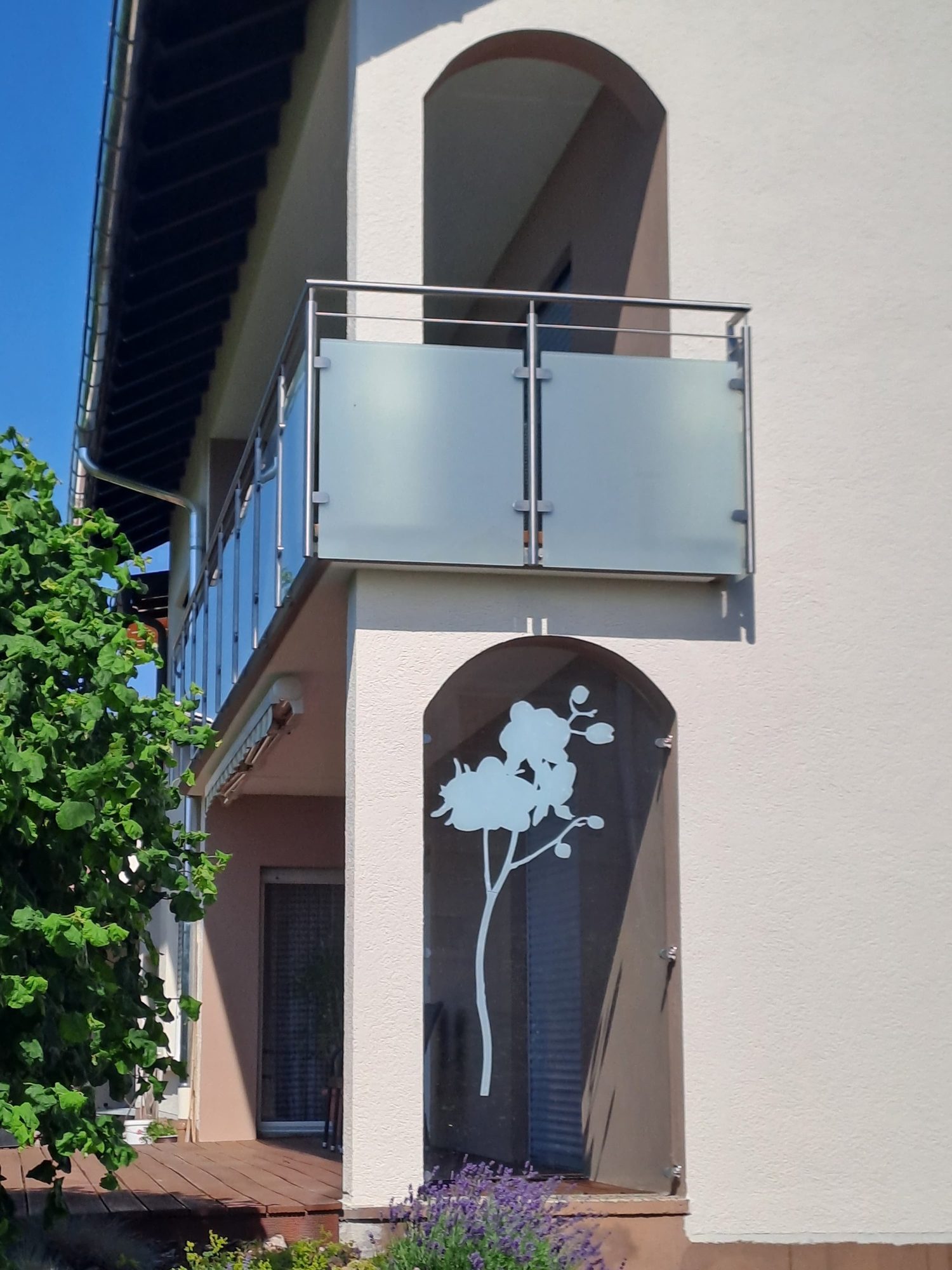 Milchglas-Balkongeländer und Motivglas mit Orchideen-Motiv in einer Bogennische