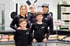 Eine lächelnde Familie mit drei Jungen in schwarzen Hemden vor einer Metzgerei-Theke mit Fleisch und "2009" Logo.