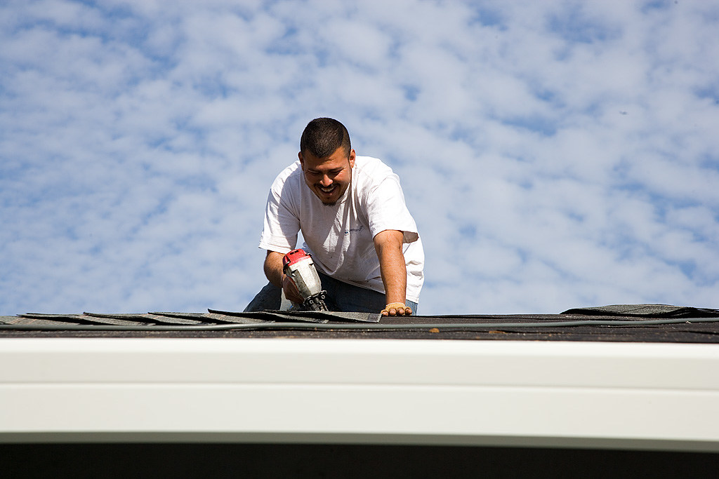 Roofer working along a roof slope tracing the source of a leak