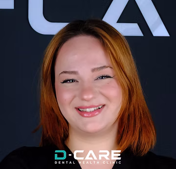Lachende junge Frau mit rötlich-braunen Haaren, weißem Lächeln und D-CARE-Logo.