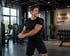 Muskulöser Mann in schwarzer Sportkleidung trainiert mit Kabelzug im Fitnessstudio. Wandtext: "STRONG FOCUSED HAPPY".