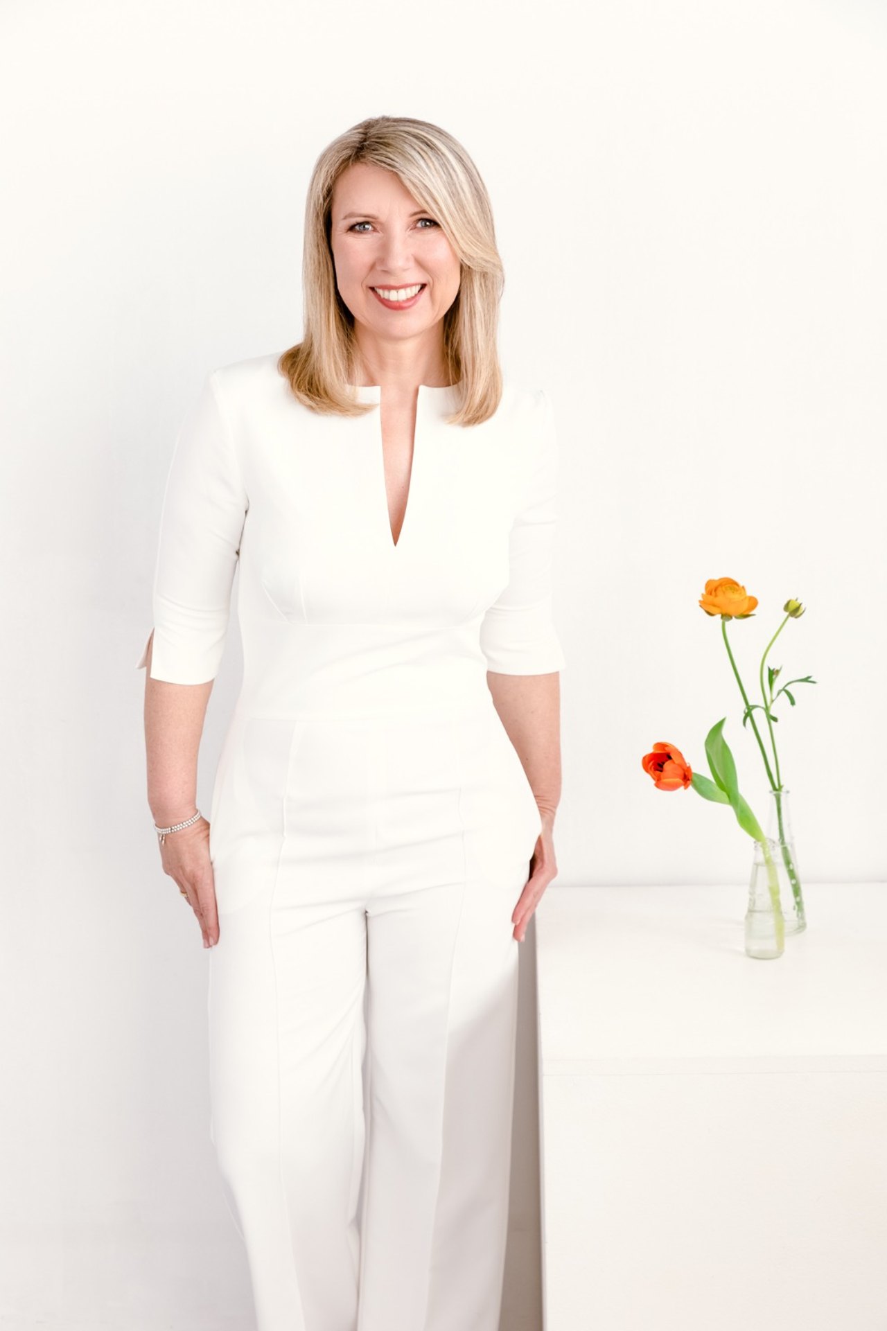 Susanne Kettler in weißem Anzug neben einer Blumenvase