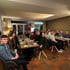 Eine Gruppe von etwa 30 Personen sitzt an langen Holztischen in einem Restaurant.