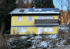 Gelbes Haus auf einem schneebedeckten Hügel mit blauen Akzenten, Dachfenstern und Solarpaneelen auf dem Dach.