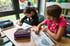 Zwei Mädchen sitzen am Tisch und malen mit Buntstiften in Malbüchern.