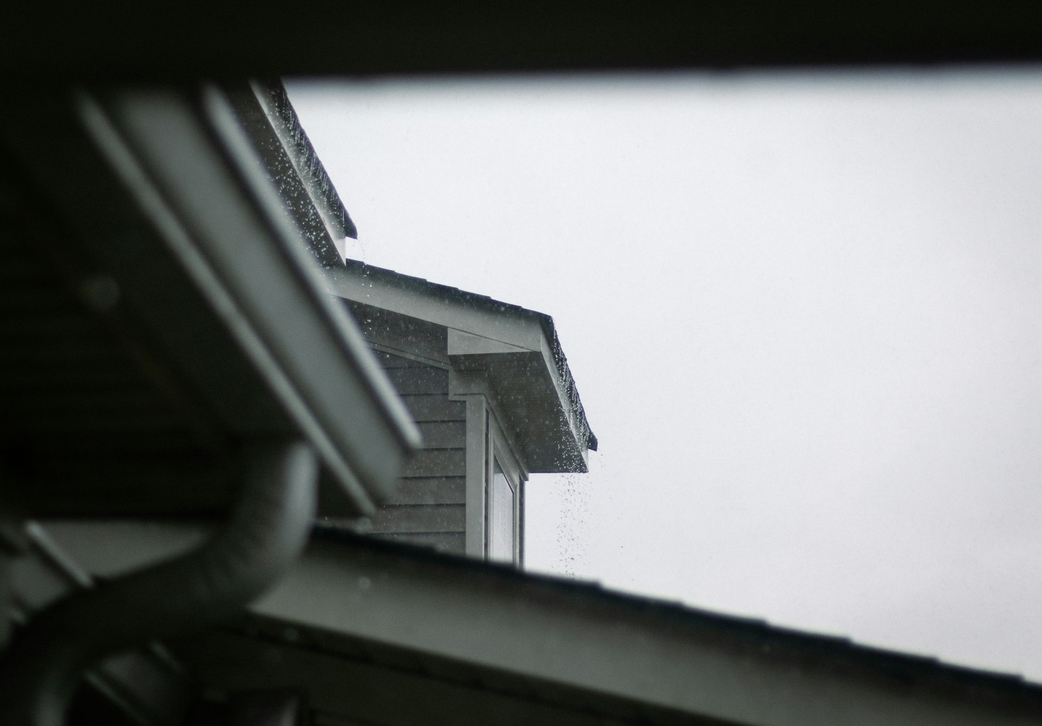 Roof edge and gutter run on a house against an overcast sky