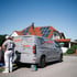 Ein Handwerker steht neben einem grauen Uniglobal-Transporter vor einem Haus mit Photovoltaik-Anlage auf dem Dach.