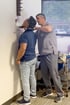 A healthcare provider in gray scrubs adjusts a cervical traction device on a patient's neck against a clinic wall.