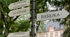 Wegweiser mit Schildern "REZEPTION GÄSTEHAUS", "AKADEMIE", "BASILIKA", "LABYRINTH" vor einem Gebäude.
