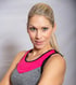 Blonde Frau mit Pferdeschwanz und grau-pinkem Sport-BH lächelt in die Kamera.