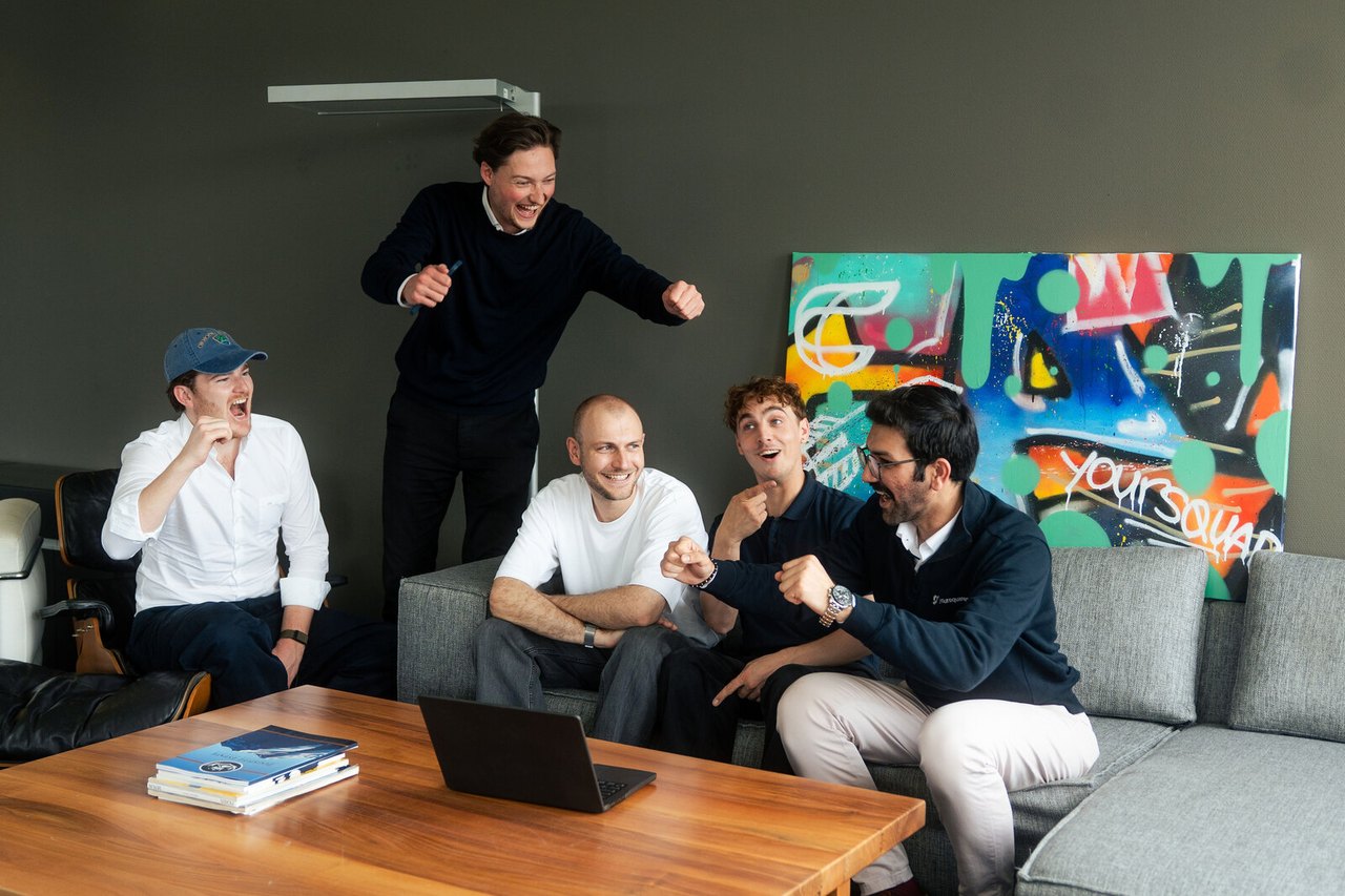 Team feiert gemeinsam an einem Laptop bei einem Abend-Event