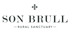 Logo mit "SON BRULL" in Großbuchstaben, darunter "RURAL SANCTUARY" und ein Kreuzsymbol oben.