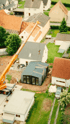 Luftaufnahme einer Baustelle mit einem Kran, der ein vorgefertigtes Modul neben einem Haus platziert.