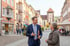 Ein Mann im Anzug unterhält sich mit einer Frau auf einem gepflasterten Marktplatz vor bunten Gebäuden und einem Turm in Villingen-Schwenningen.