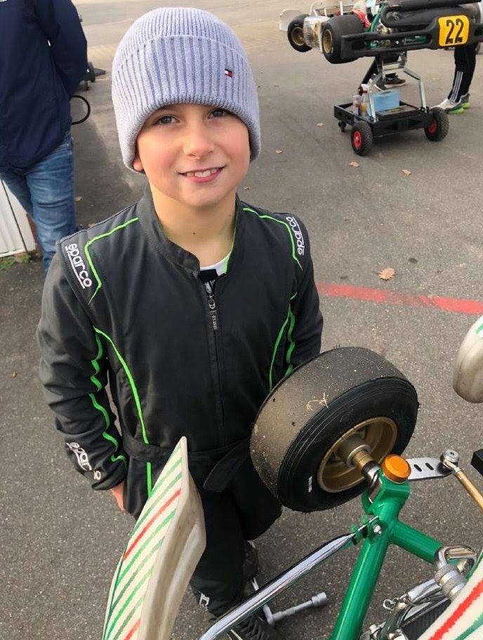 Marlon mit Mütze neben seinem Kart im Fahrerlager