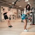 Zwei Frauen trainieren mit TRX-Bändern in einem Fitnessstudio.