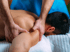 Therapist's hands massaging a man's shoulder, focusing on muscle knots.